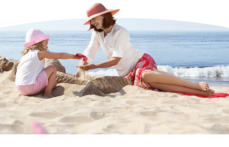 Frau und Kind spielen zusammen am Strand mit Kompressionsstrümpfen